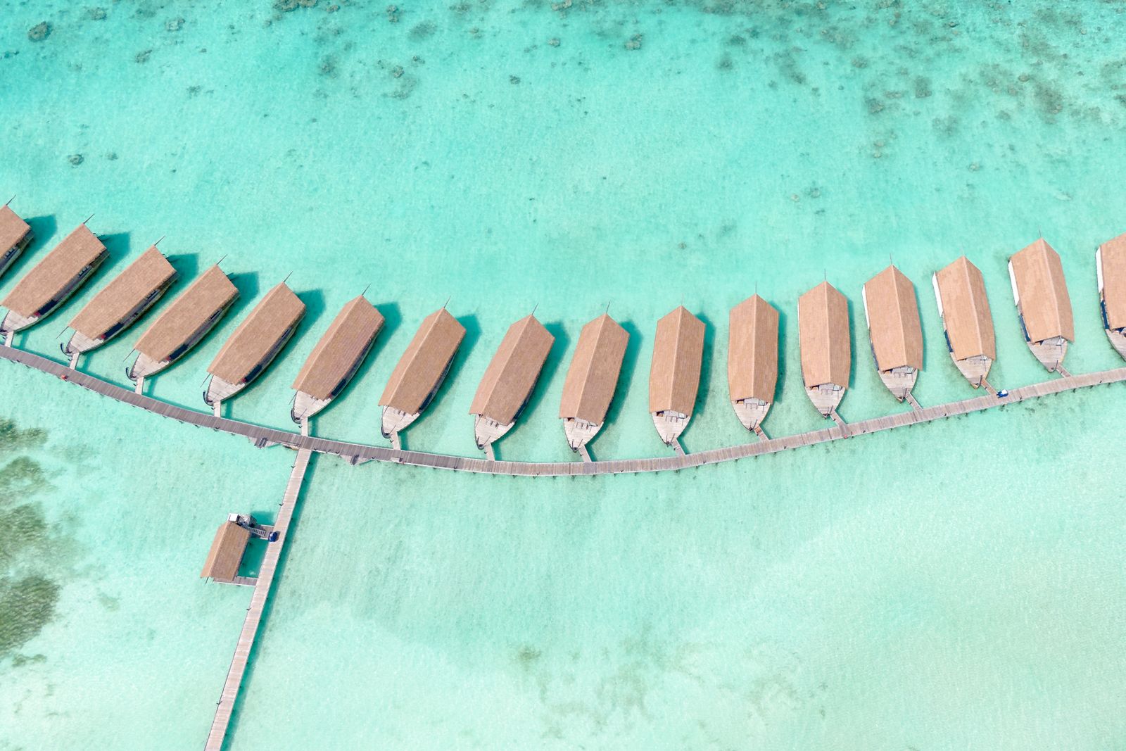 An aerial view of clear water surrounding island villas